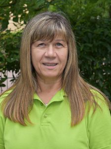 Frau mittleren Alters mit langen hellbraunen Haaren und grünem Poloshirt